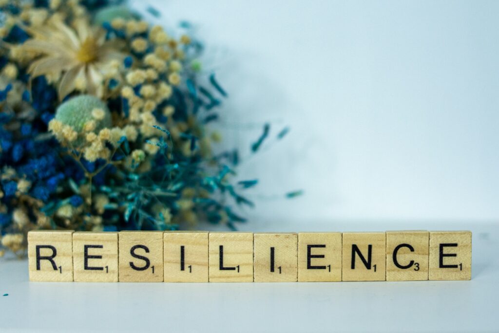 Word 'Resilience' spelled out with wooden letter tiles, with a soft floral background