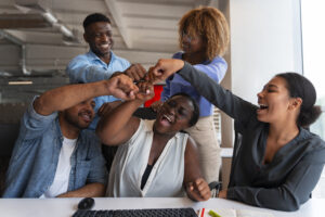 Diverse team celebrating success with group fist bump in modern office