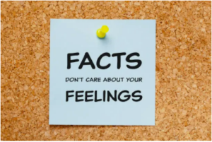 Sticky note pinned to a corkboard reading “Facts don’t care about your feelings.”