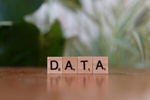 Wooden letter blocks spelling “DATA” on a table with a blurred green background.