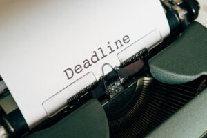 Close-up of a typewriter with paper showing the word 'Deadline' typed in black text.